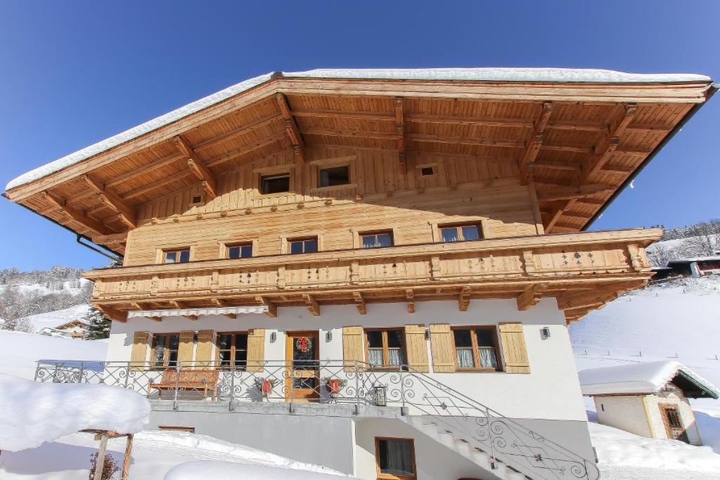 ein Haus mit einem Holzdach im Schnee in der Unterkunft Obertaxinghof in Saalbach-Hinterglemm