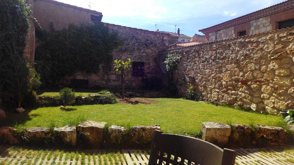 a chair sitting in a yard next to a stone wall at La Casa de la Abuela Petra in Solarana