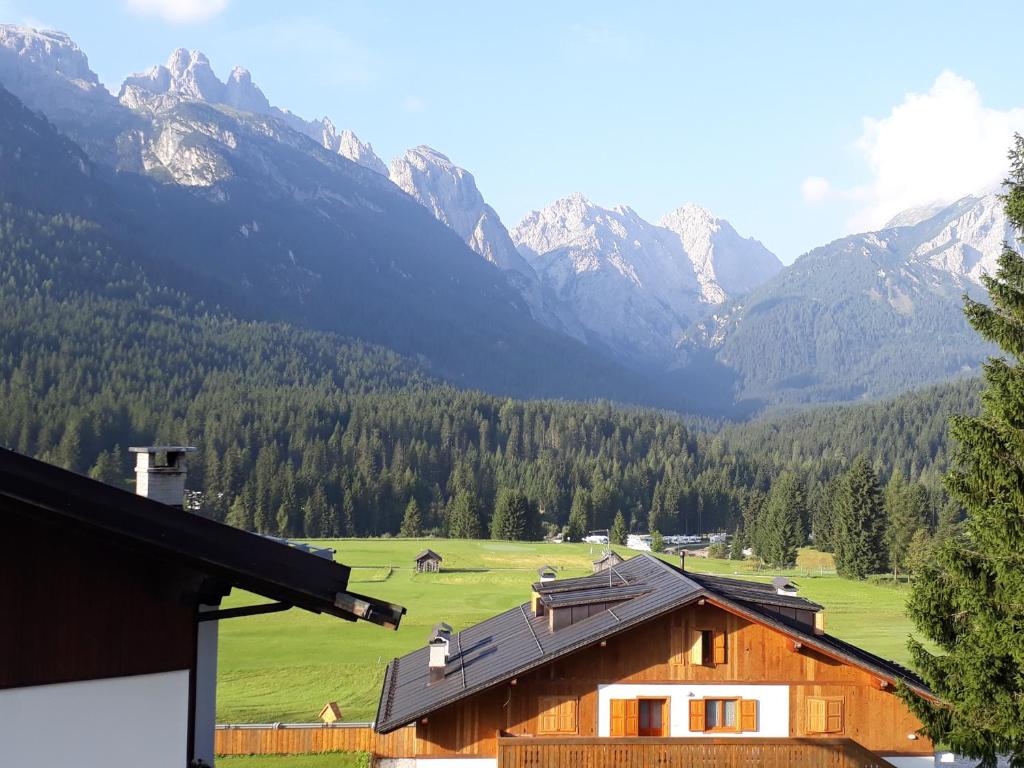 a wooden house with mountains in the background at Appartamento centrale Sappada in Sappada