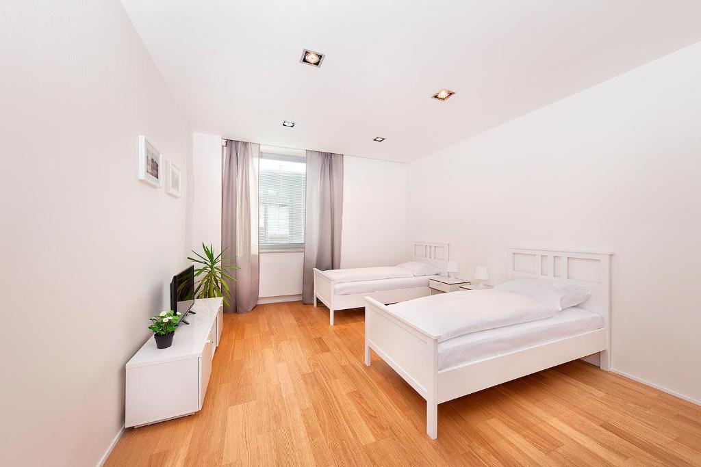 a white living room with white furniture and wood floors at Hotel & Hostel Letov in Prague