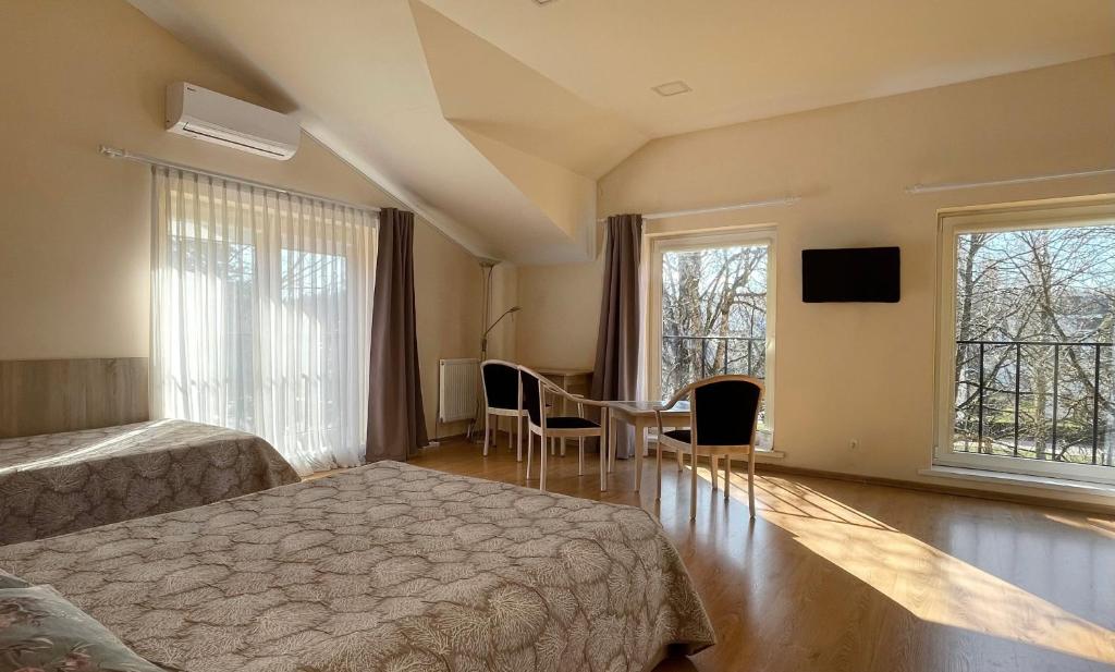 a bedroom with two beds and a table and two windows at Parko Studija in Birštonas