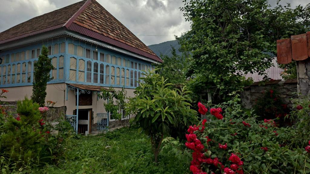 a house with a blue roof and some flowers at Guest House Ruh Achari in Sheki