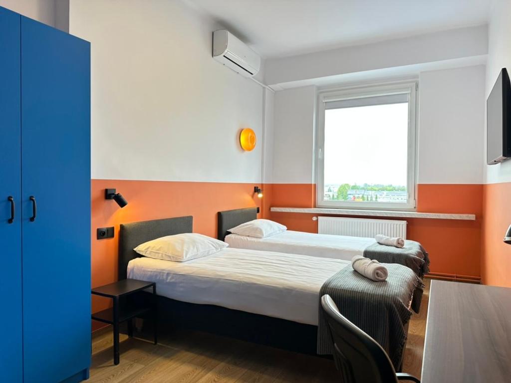 two beds in a room with orange and white walls at Pokoje & Bistro Mielec in Mielec