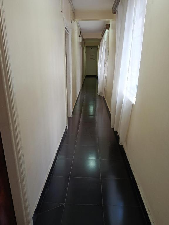a hallway with a long corridor with white walls and black tiles at City Brisa cbd in Nairobi