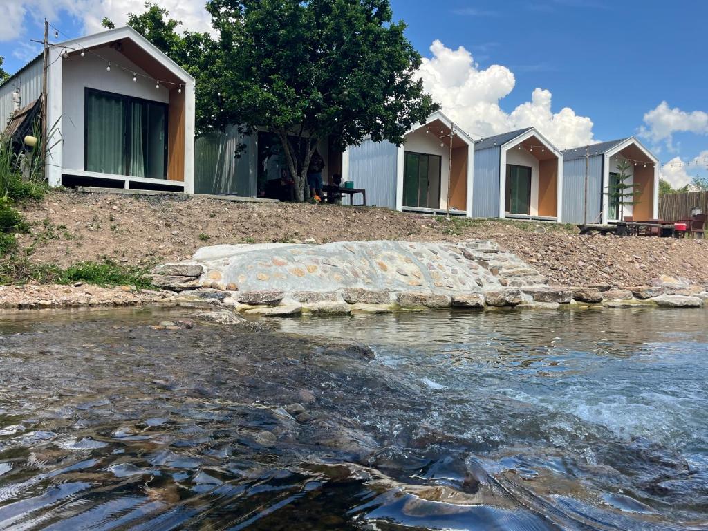 a row of houses on a hill next to a river at มาแคมป์ ชะอม in Ban Bung Mai