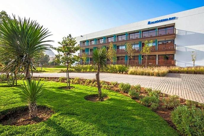 a building with palm trees in front of it at Hôtel Souani ( Al Hoceima Bay) in Al Hoceïma