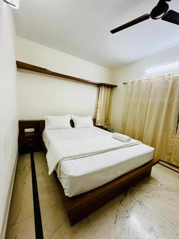 a bedroom with a large bed with white sheets at U K I Guest House in Bangalore