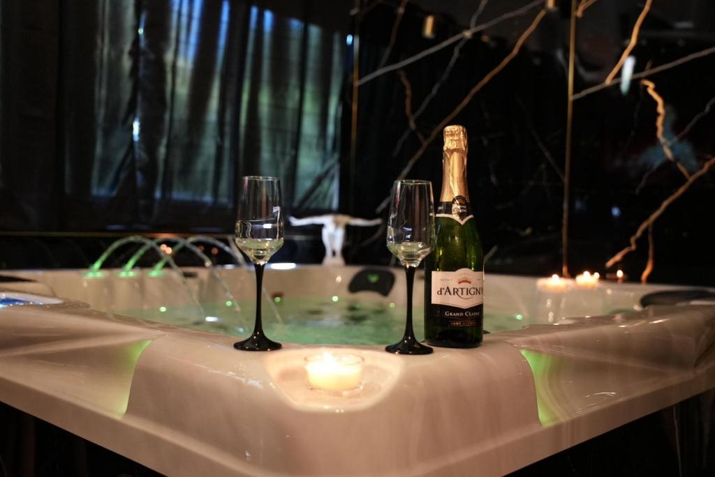 a bottle of champagne and two glasses on a table at Dahlia suite & spa in Nîmes