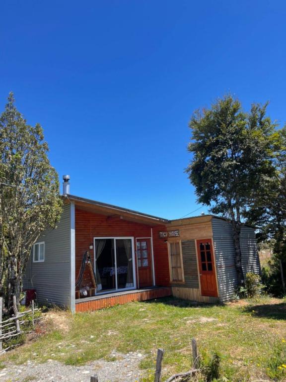 a house with a tree in front of it at Cabañas y tinajas in Ancud