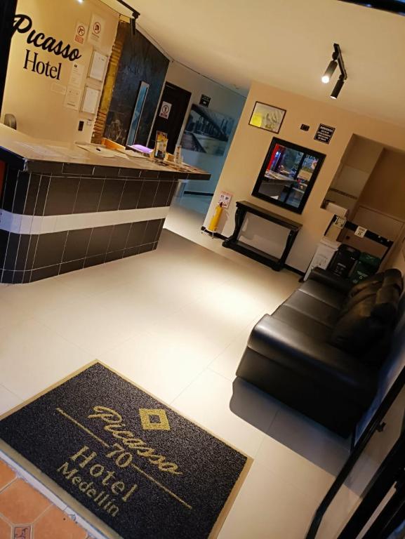a living room with a black leather couch and a table at Hotel Picasso 70 in Medellín