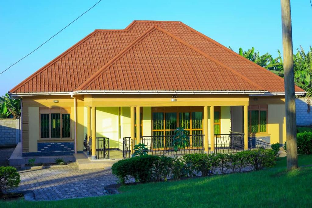 a yellow house with an orange roof at standalone in Fort Portal