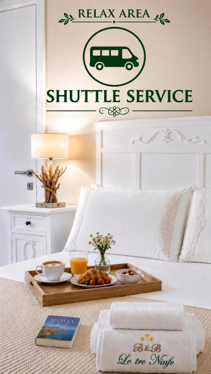 a tray of food on a bed with a shuttle service sign on it at LE TRE NINFE Cinisi in Cinisi