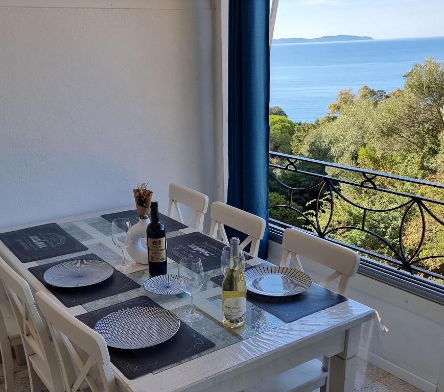 a table with plates and wine bottles on a balcony at Résidence des îles - Samos III in Ajaccio
