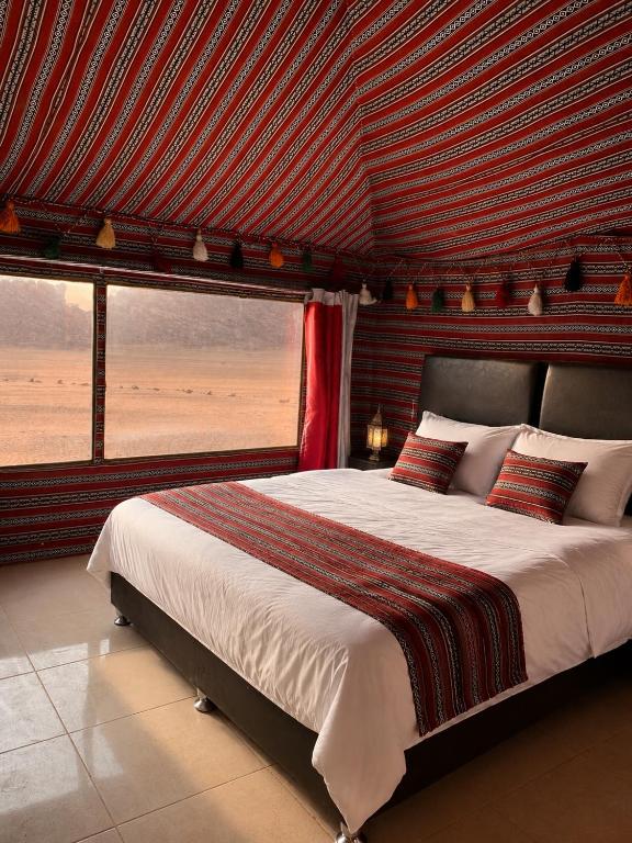a bedroom with a large bed and a large window at Starry Nights Camp in Wadi Rum