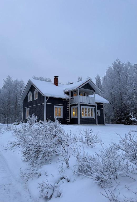 a black house with snow on the ground at Treeline Cottage in Rovaniemi
