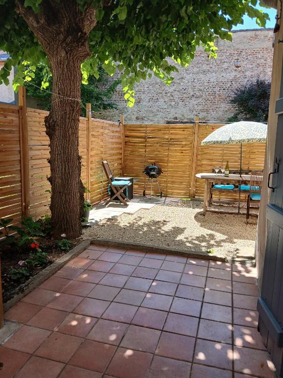 a patio with a tree and a table and a bench at Apartment with a garden in Moulins