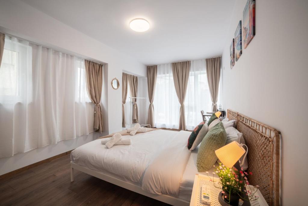 a bedroom with a bed with white sheets and windows at Central Summer Theatre Suites in Veliko Tŭrnovo