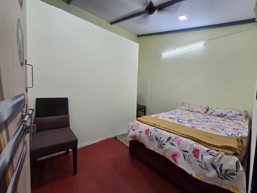 a small bedroom with a bed and a chair at Pilankar Guest House in Ratnagiri