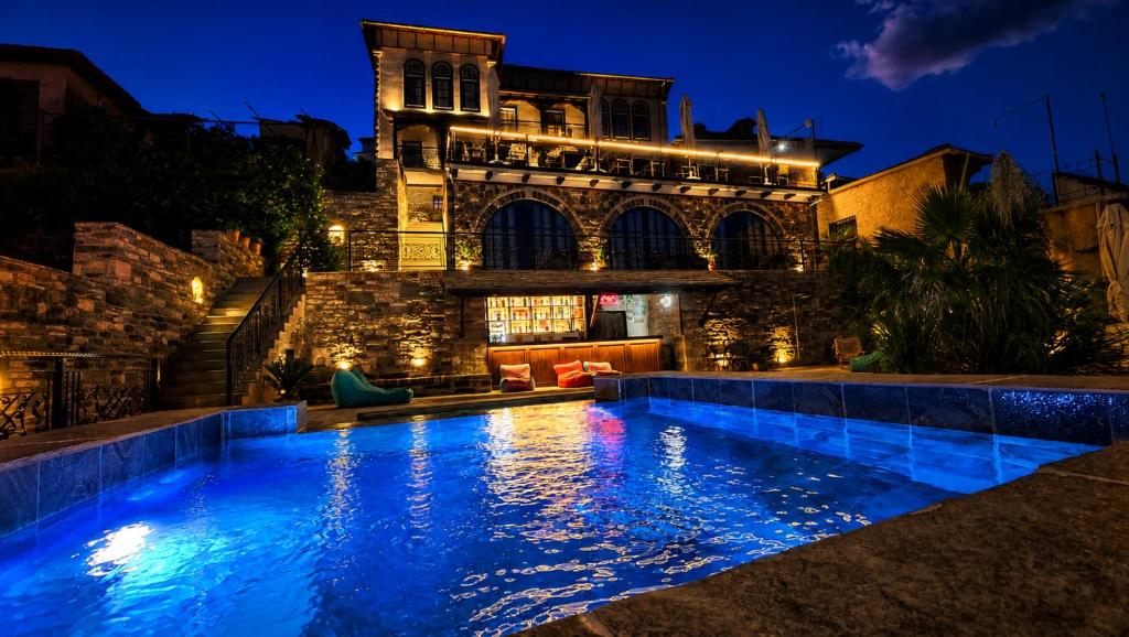 a swimming pool in front of a building at night at Cumaku Boutique Hotel & Spa in Gjirokastër