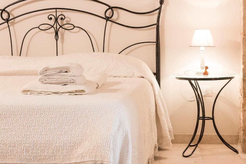 a bedroom with a white bed and a table with a lamp at Le Dimore del Finoglio in Conversano