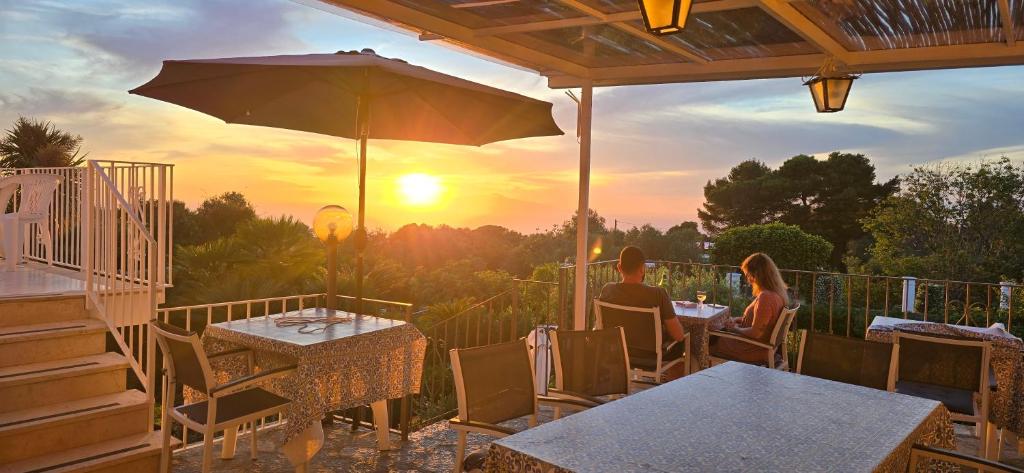 a man and woman sitting at a table with an umbrella at villa damecuta B&B in Anacapri