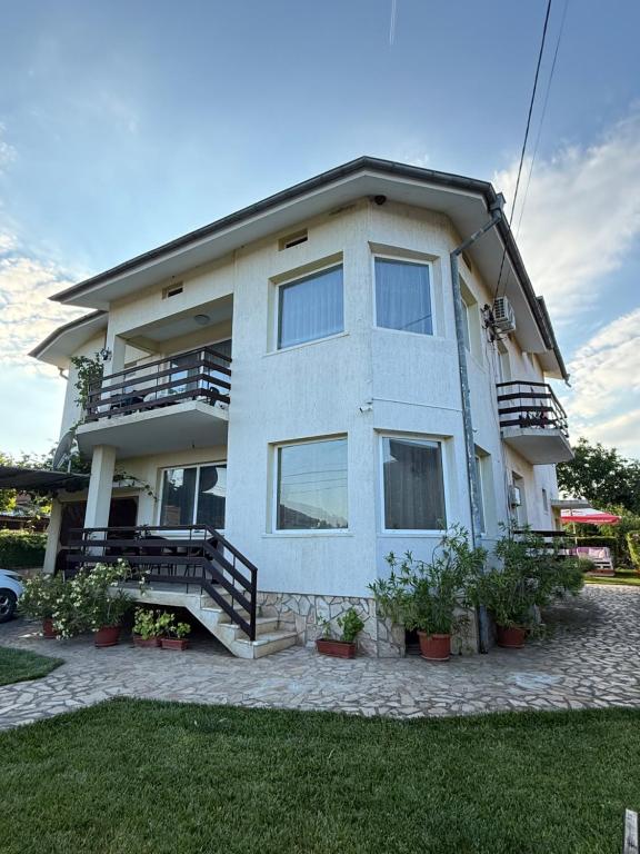 a large white house with stairs and plants in a yard at Къща за гости Шишкови in Shabla