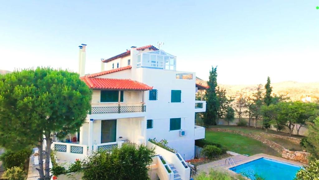 a white house with a swimming pool in front of it at Villa Evmaria in Áyios Konstandínos