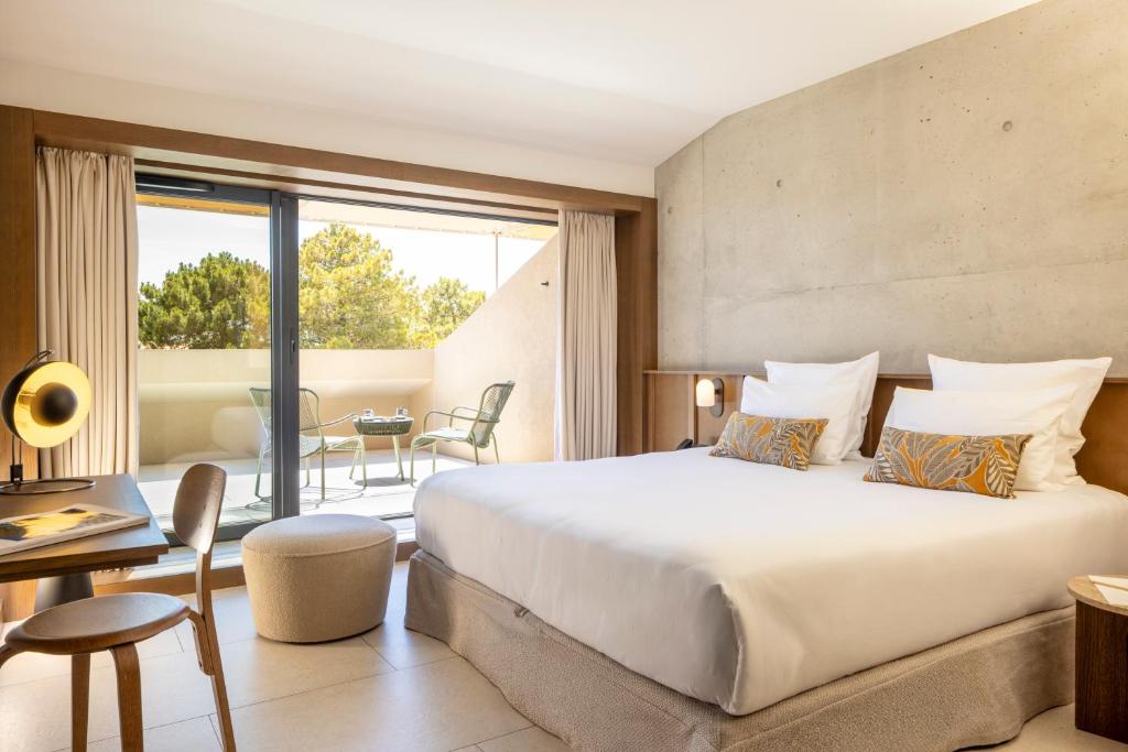 a bedroom with a large bed and a balcony at Hôtel Spa & Restaurant - Son de Mar in Porto-Vecchio