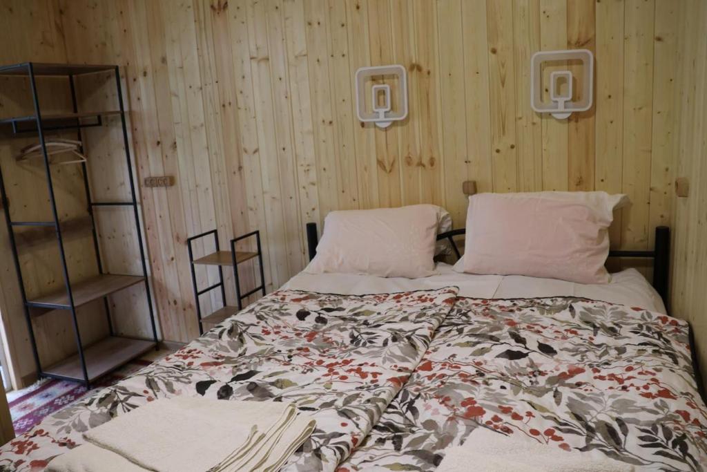 a bedroom with a large bed with a floral comforter at Wooden house in Kutaisi