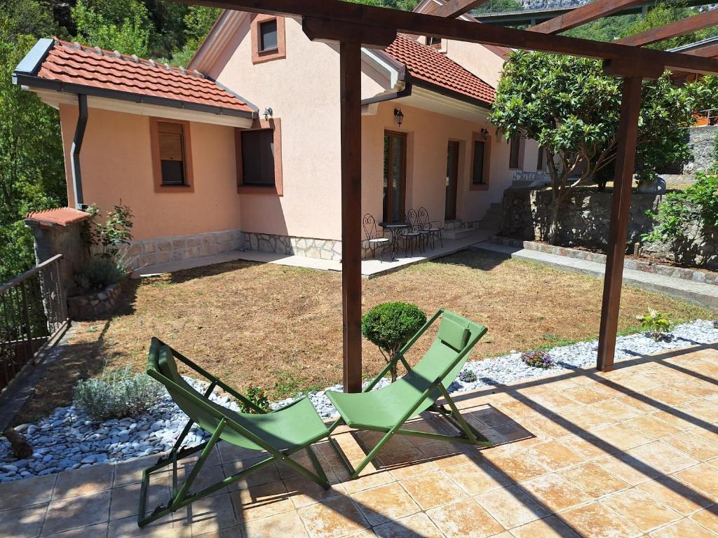 two green chairs sitting on a patio in front of a house at Salatić-Lekić apartmani in Čanj