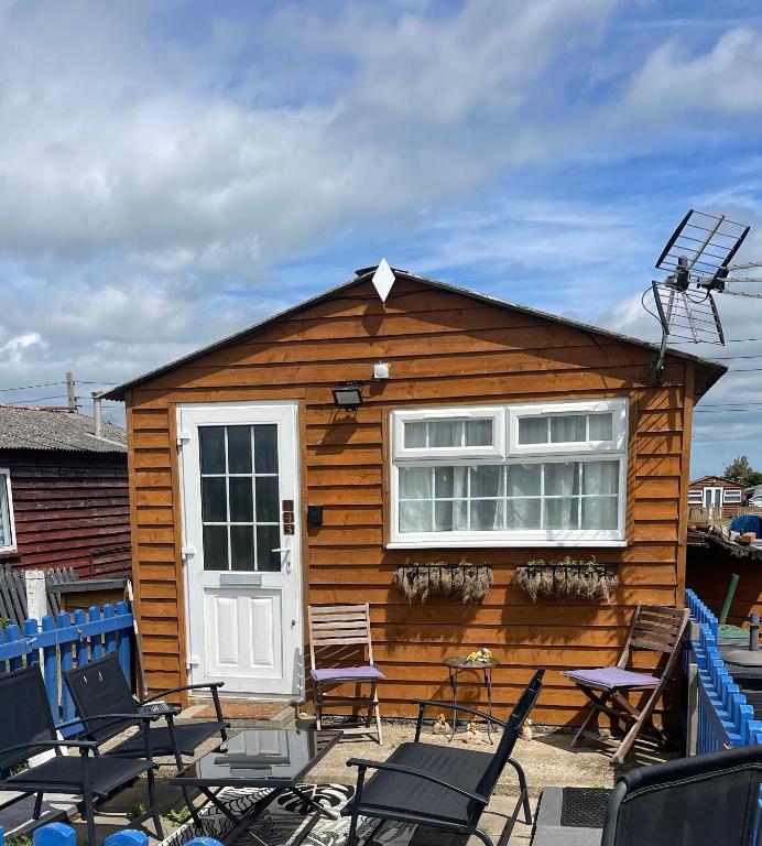 a log cabin with chairs and a white door at Sheppey Village Roxy in Leysdown-on-Sea