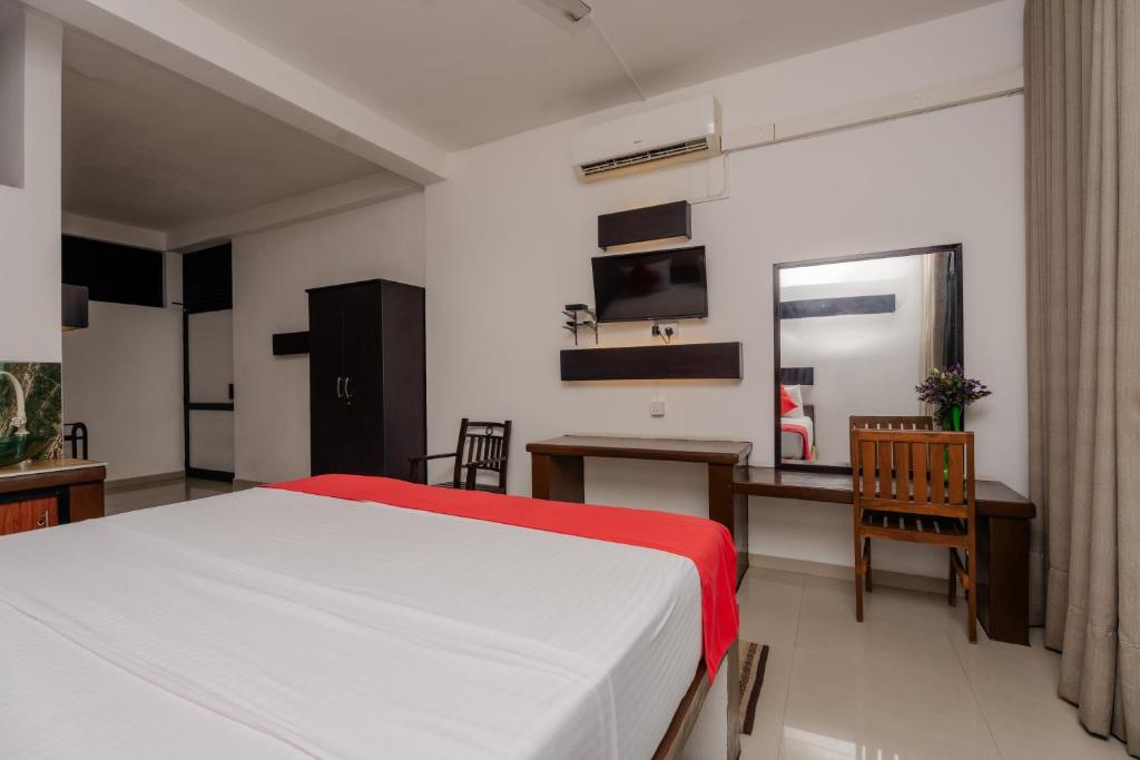 a bedroom with a bed and a table and a desk at Sahana beach in Galle
