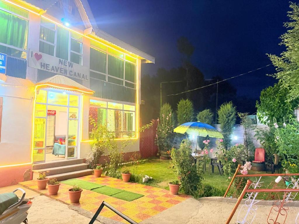 a house with a yard with a table and an umbrella at Hotel New Heaven Canal in Srinagar