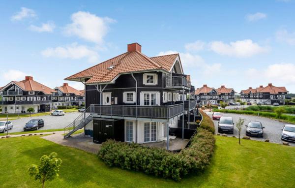 ein großes schwarzes Haus mit Autos auf einem Parkplatz in der Unterkunft Bogense strand in Bogense