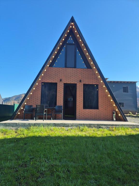 a red brick building with a pitched roof with chairs at Emerald Cottages in Borjomi