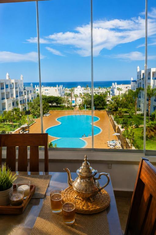a table with a tea pot on a table in front of a window at Spacious Apartment with views to sea and pool Kabila vista Families only in Marina Smir