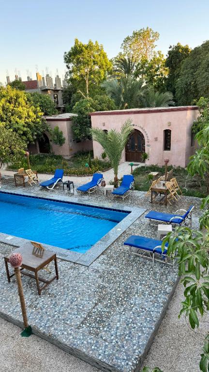 a swimming pool with blue chairs and a house at El Juneina Villas - Luxury Boutique Villas Near Valley of the Kings in Luxor
