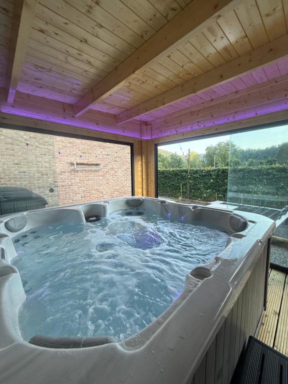 a hot tub on a deck with a large window at L'Aurore Céleste in Aywaille