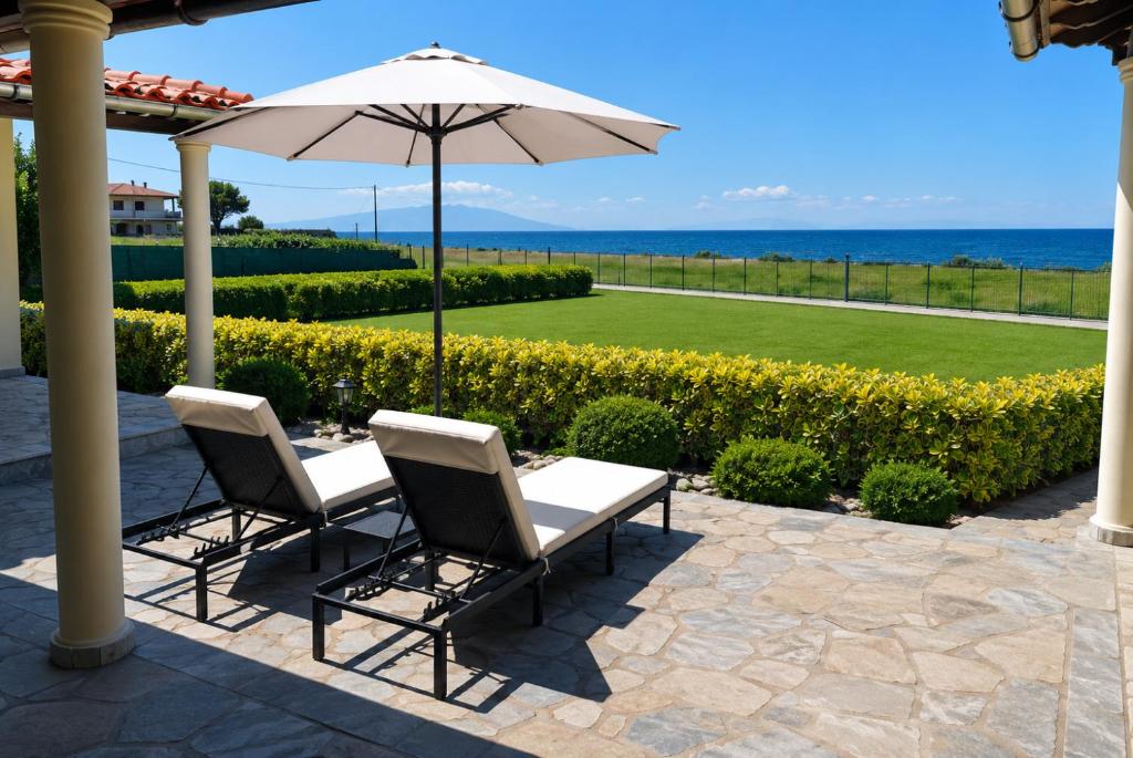 two chairs and an umbrella on a patio at Luxury Villa Ntina in Maronia