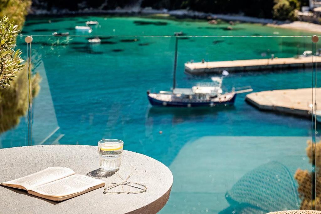 a glass of wine sitting on a table next to the water at Casa Nina in Patitiri