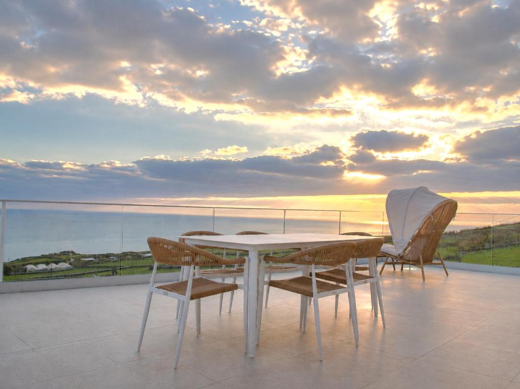 a white table and chairs on a balcony with the sunset at Casa Conchita in Angra do Heroísmo