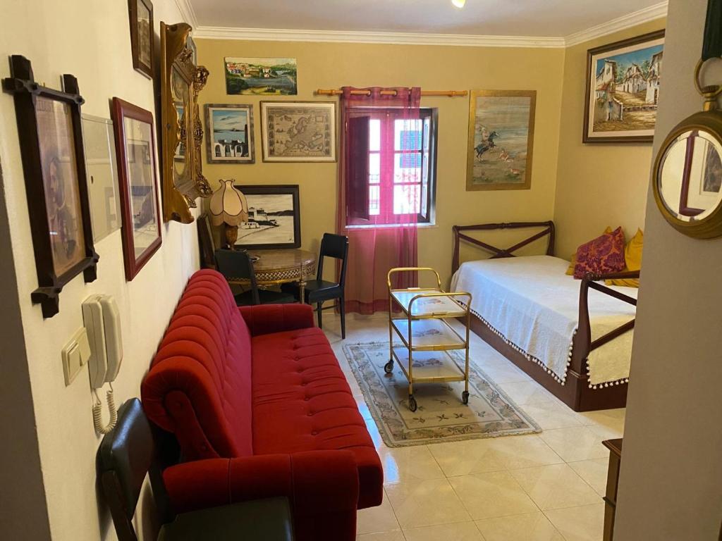 a living room with a red couch and a bed at Vintage Apartment in Vila Nova de Milfontes