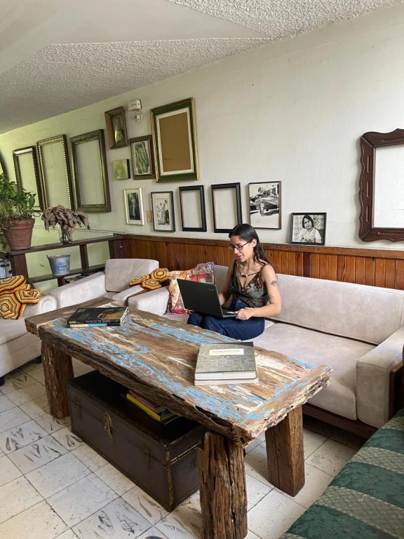 a woman sitting on a couch with a laptop on a table at Hostal Casa Las Tías in Medellín