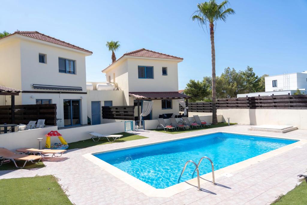 a villa with a swimming pool in front of a house at Villa Paradise Complex - Pyla Larnaca in Pyla