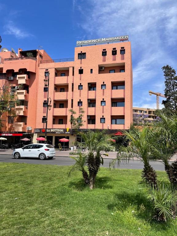 a white car parked in front of a large building at Hôtel Résidence Marrakech in Marrakesh