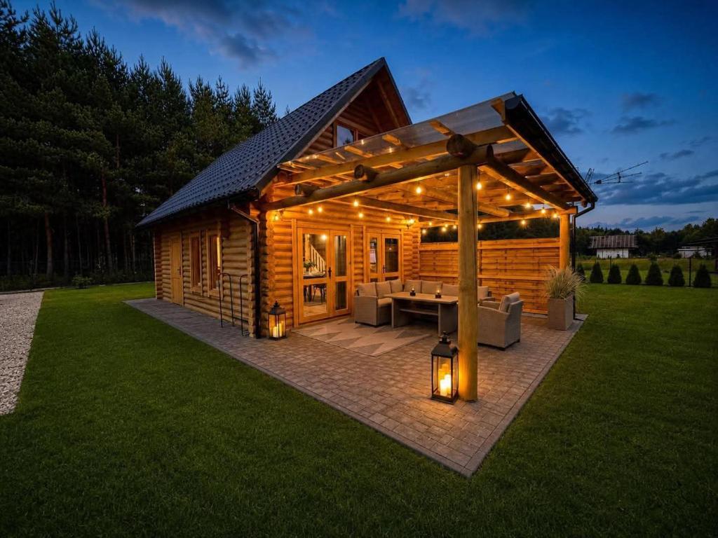 a wooden cabin with a deck with lights on it at Radawski Chill in Radawa