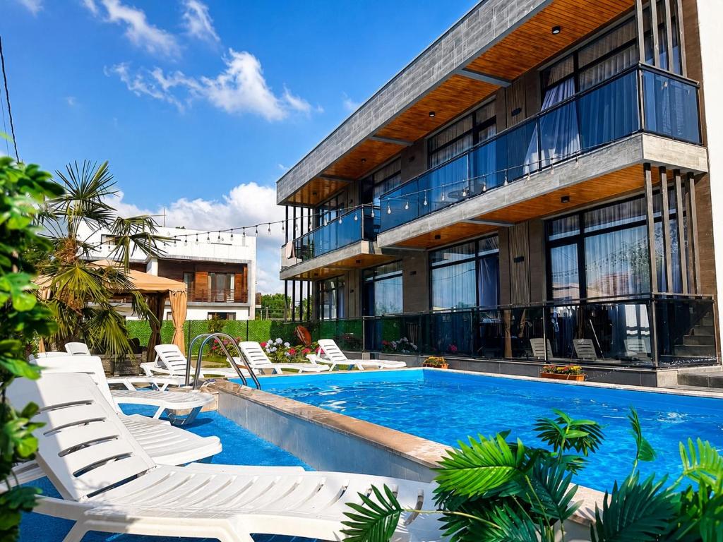 a house with a swimming pool and white chairs at Apollo Cottages Kaprovani in Urekis Sadguri