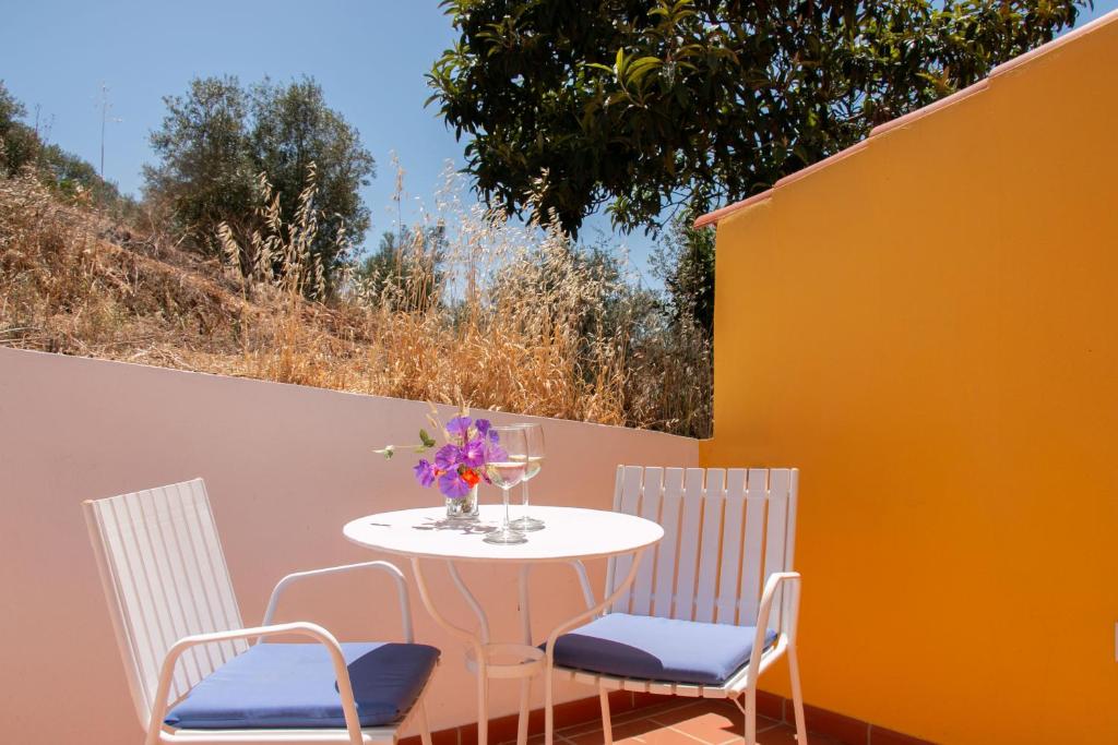 two chairs and a table with a vase of flowers on a patio at Manas Slowliving - Santiago in Santiago do Cacém