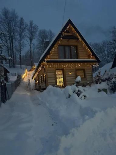 a house covered in snow with lights on it at Śleboda Home&Spa in Gliczarów Górny