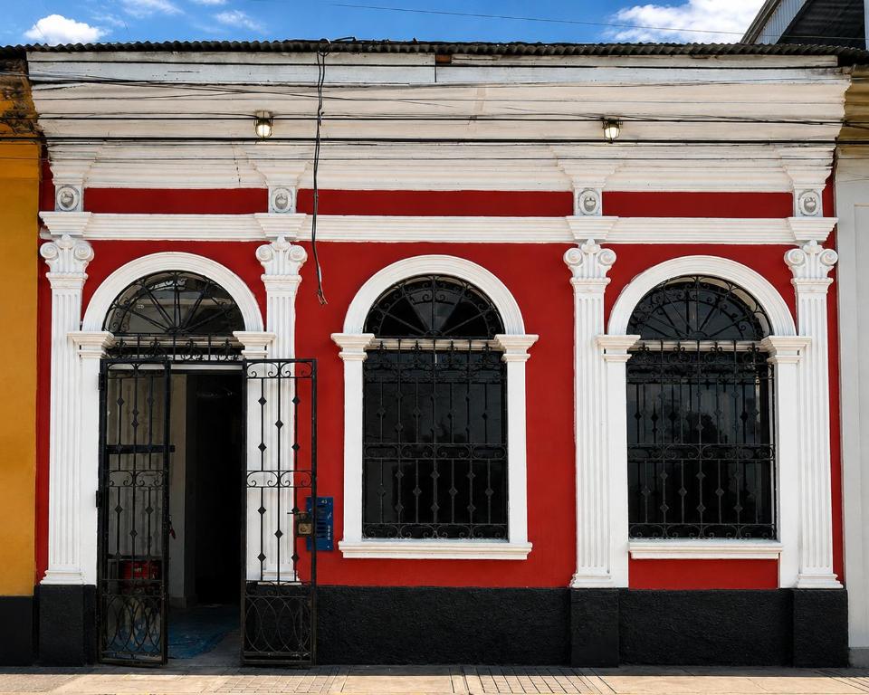 a red and white building with three windows at Nau Guest House & Restaurant in Iquitos